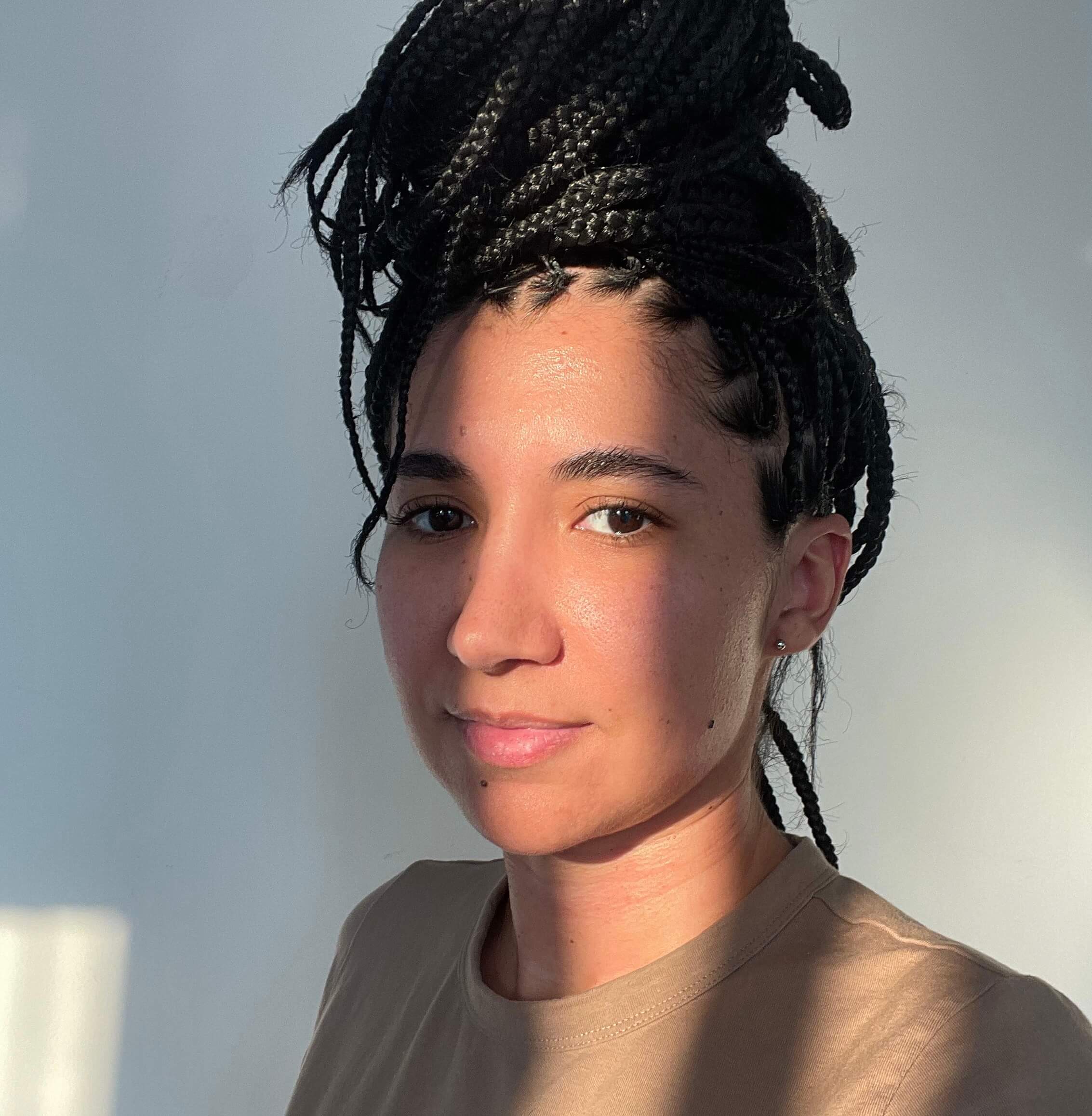 Imagem de perfil de Thalita Torres com um fundo claro, usando uma blusa marrom e olhando para a câmera